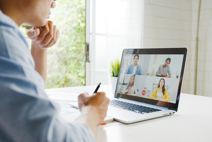 Young Asia businessman using laptop talk to colleagues about plan in video call meeting while work from home at living room. Self-isolation, social distancing, quarantine for corona virus prevention.